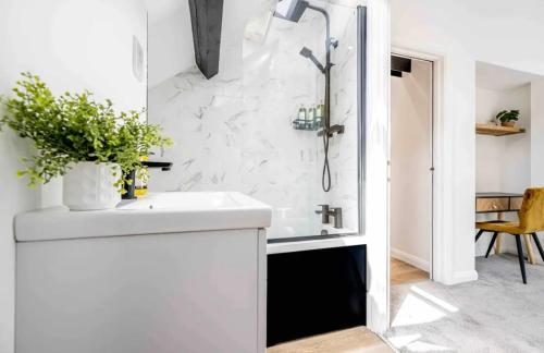 a white bathroom with a shower and a sink at The Old School Sleeps 14 in Lymington