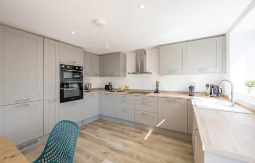 a kitchen with white cabinets and a wooden floor at The Old School Sleeps 14 in Lymington