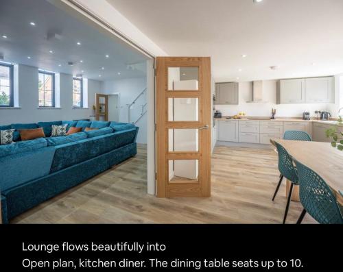 a living room with a blue couch and a dining table at The Old School Sleeps 14 in Lymington