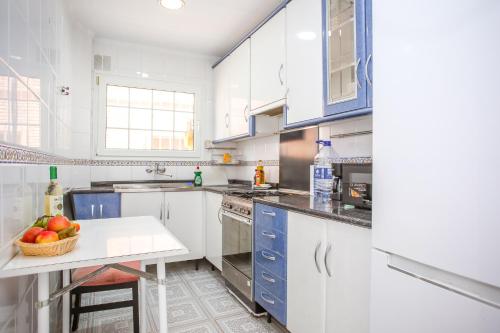 a kitchen with white cabinets and a bowl of fruit on a table at Central Beach Modernist Apartment in Lloret de Mar