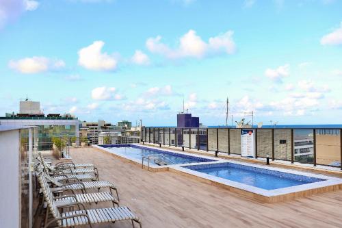 a balcony with chairs and a pool on a building at Buenos Ayres por Carpediem in Tambaú