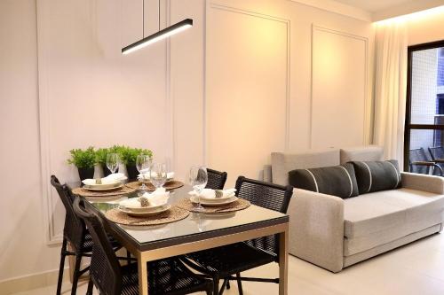 a dining room with a table and chairs and a couch at Buenos Ayres por Carpediem in Tambaú