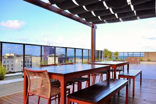 a deck with a table and chairs on a balcony at Buenos Ayres por Carpediem in Tambaú