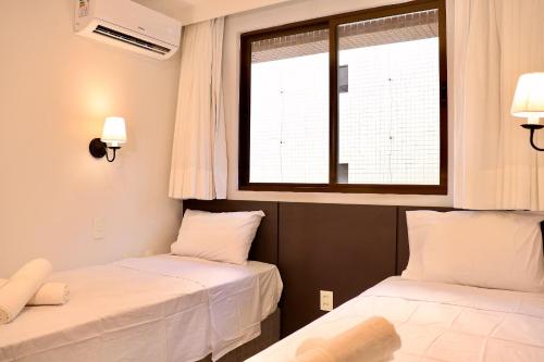 two beds in a room with a window at Buenos Ayres por Carpediem in Tambaú