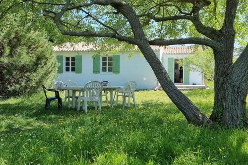 a table and chairs in front of a white house at Jolie maison, 500 m de la plage, grand jardin in Les Portes