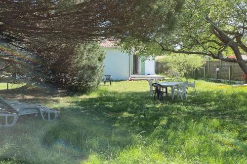 une table de pique-nique et des chaises dans l'herbe sous un arbre dans l'établissement Jolie maison, 500 m de la plage, grand jardin, aux Portes