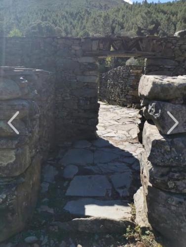 a stone wall with a bridge over a river at Casa rural La calleja de las hurdes TRCC00555 in Sauceda