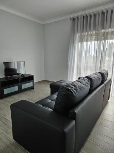 a living room with a black leather couch and a television at Residencias Ana Carmen in Viana do Castelo