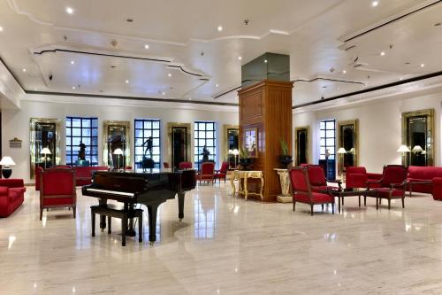a lobby with a grand piano and red chairs at Meliá Caracas in Caracas