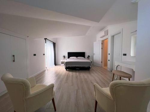 a large white room with a bed and two chairs at HACI BEY VİLLALARI in Kemer