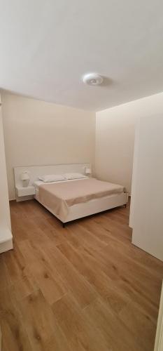 um quarto branco com uma cama e piso em madeira em Family Vacation New House em Durrës