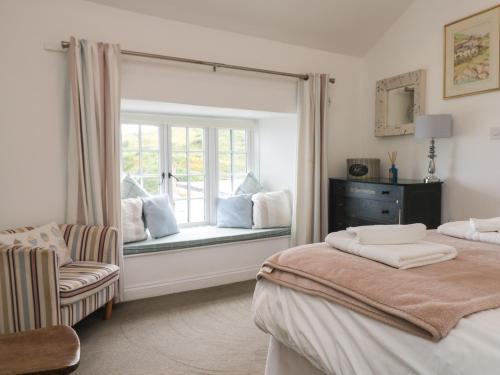 una camera con due letti e una finestra con una sedia di Kerbenetty Harbour Cottage a Portloe