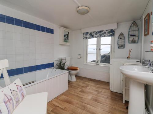 a bathroom with a sink and a tub and a toilet at Kerbenetty Harbour Cottage in Portloe