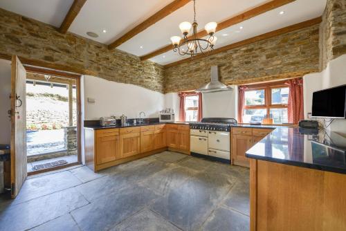 a large kitchen with wooden cabinets and a stove top oven at Haye Barton Farm in Liskeard