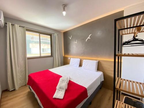 um pequeno quarto com uma cama com um cobertor vermelho em Diamond Beach em Vila Velha