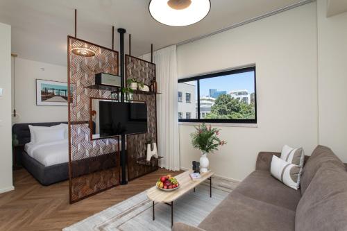 een woonkamer met een bank en een televisie bij De Sheinkin in Tel Aviv