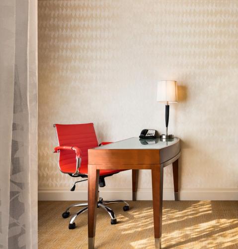 a red chair sitting next to a desk with a phone at Viana Hotel and Spa, Trademark Collection by Wyndham in Westbury