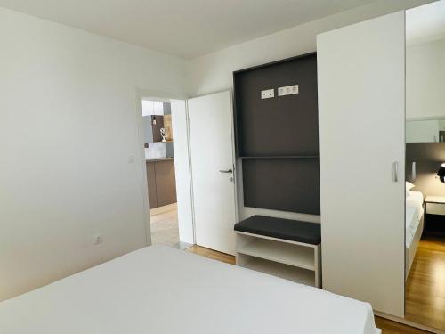 a bedroom with a white bed and a black closet at Apartmani AViS in Selce