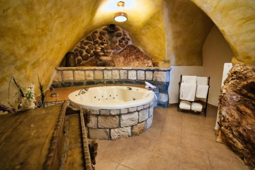 a bathroom with a stone tub in a stone wall at Hameiri Estate in Rosh Pinna