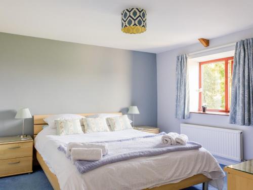 金斯布里奇的住宿－Honeysuckle Cottage，一间卧室配有一张蓝色墙壁的床和一扇窗户