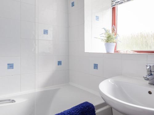 Honeysuckle Cottage في كينغسبريدج: حمام أبيض مع حوض وحوض استحمام ومغسلة