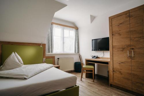 a bedroom with a bed and a desk and a television at Gästehaus Thomahan in Friesach