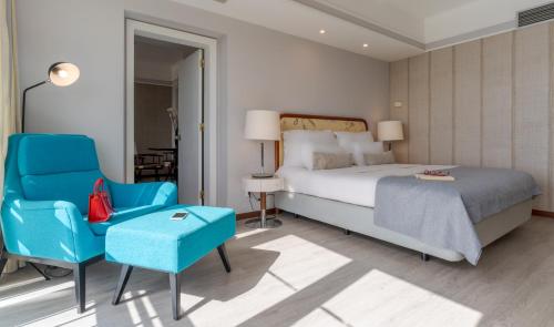 a bedroom with a bed and a blue chair and a bed and a table at Pestana Alvor Praia Premium Beach & Golf Resort in Alvor