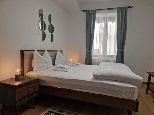 a bedroom with a bed with white sheets and a window at Maximus Apartments in Sighişoara