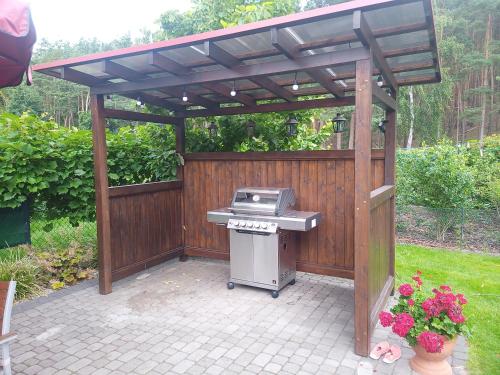 a barbecue grill under a wooden pergola in a backyard at Pokoje Sobie na Wyspie in Gdańsk
