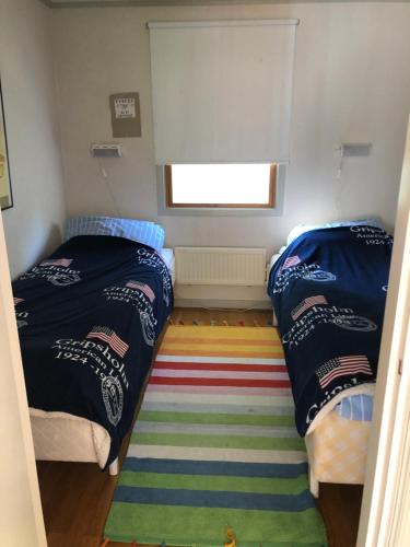 2 camas en una habitación pequeña con alfombra en Semesterhus i Stockholms skärgård, Runmarö., en Nämdö