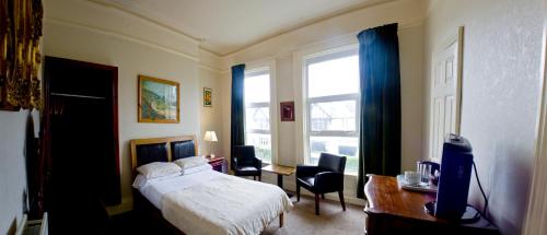 a bedroom with a bed and a desk and a window at Somerton House Rooms Only in Belfast