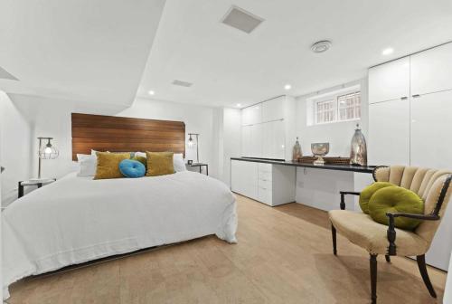 een witte slaapkamer met een bed en een stoel bij Spacious & fully equipped - Private studio apartment - lower level in Burlington