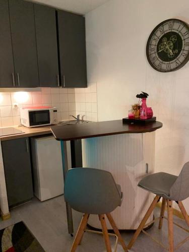 una cucina con bancone, 2 sedie e forno a microonde di Studio Aux Portes du Port de Canet-Plage avec place de parking privé a Canet-en-Roussillon