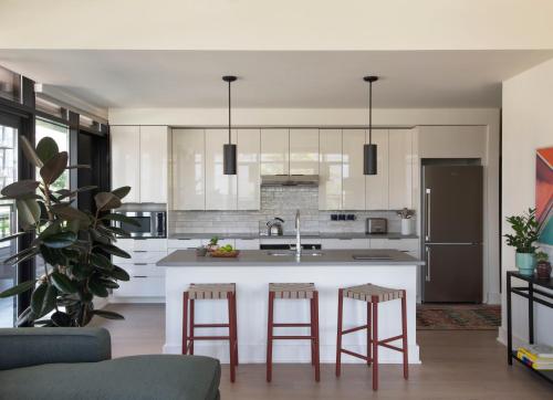 a kitchen with white cabinets and a kitchen island with bar stools at Roost Baltimore in Baltimore