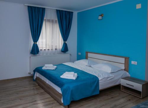 モイエチウ・デ・ススにあるCasa Edenのベッドとタオル2枚が置かれた青い寝室