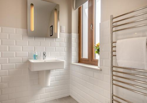 ein weißes Bad mit einem Waschbecken und einem Fenster in der Unterkunft Midsomer in Aldeburgh