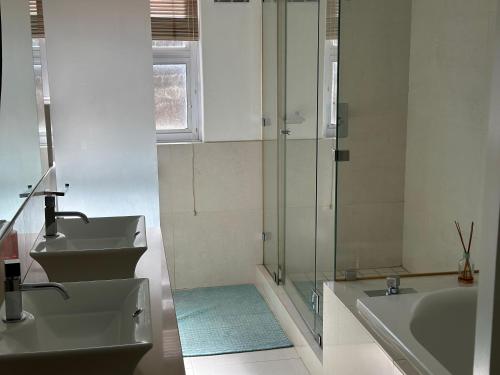 a bathroom with two sinks and a glass shower at Beach Vibes Clifton! in Cape Town