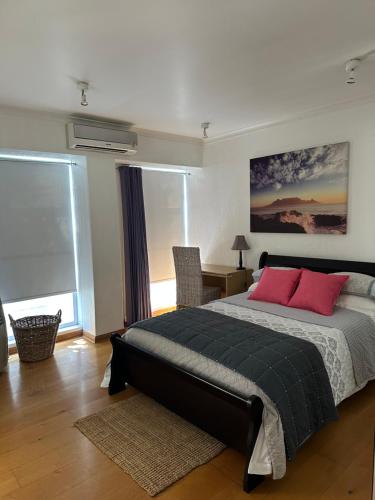 a bedroom with a large bed with two red pillows at Beach Vibes Clifton! in Cape Town