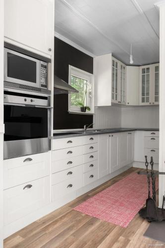 a kitchen with white cabinets and a microwave at Stuga paradis in Orkelljunga