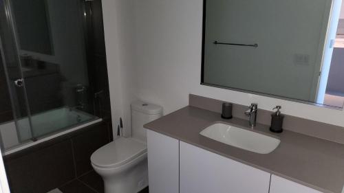 a bathroom with a sink and a toilet and a mirror at Canvas Condo in Miami
