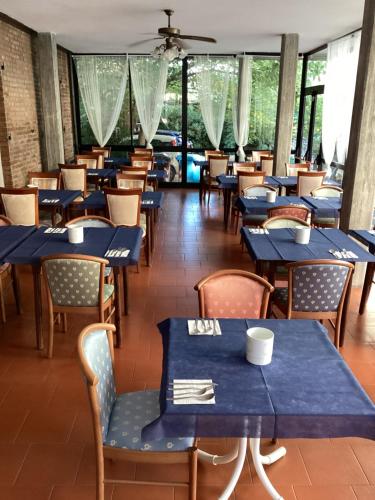 um restaurante com mesas e cadeiras azuis e janelas em Hotel Villa Alexandra em Bellaria-Igea Marina