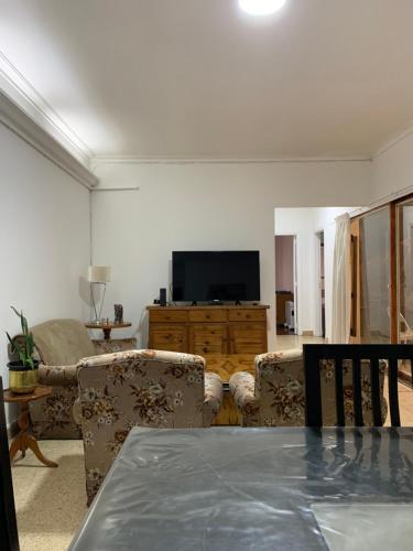 sala de estar con 2 sillas y TV en Departamento Las Heras en Mendoza