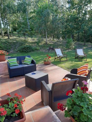 a patio with wicker chairs and tables and a yard at La Collina dei Passeri in Pocapaglia