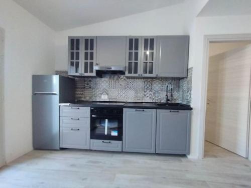 uma cozinha com armários brancos e electrodomésticos num quarto em La Villetta di Sa Marina em Bari Sardo