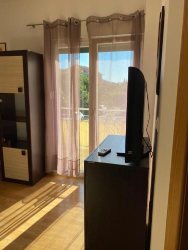 een kamer met een bureau, een televisie en een raam bij Апартаменты Дженовичи in Ðenovići