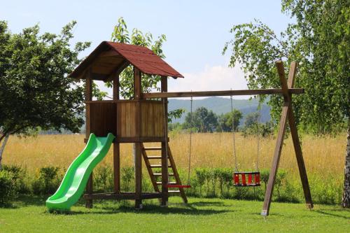 a wooden playground with a slide and a swing at Apartmani Albatros in Perušić