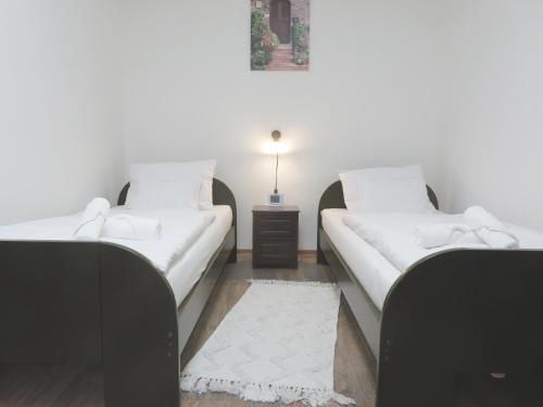 two beds in a room with a table and a lamp at Hegyköz Vendégház in Pusztafalu