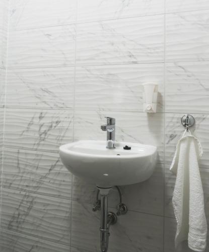 a white bathroom with a sink and a towel at Hegyköz Vendégház in Pusztafalu