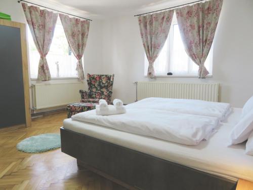 a bedroom with a large white bed and two windows at Hegyköz Vendégház 