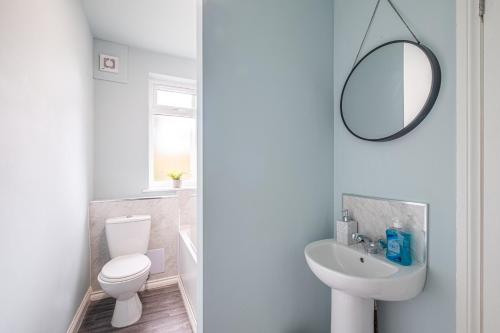 a bathroom with a toilet and a sink and a mirror at Stunning Home Ideal for Business - Free Parking in Birstall